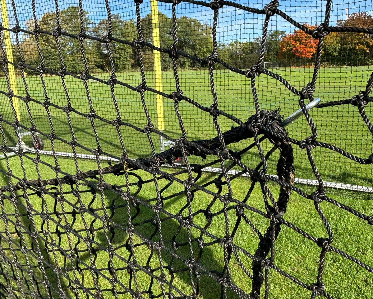 Close-up view of the netting in an 11m Anti-Vermin Mobile Batting Cage on a grassy field.