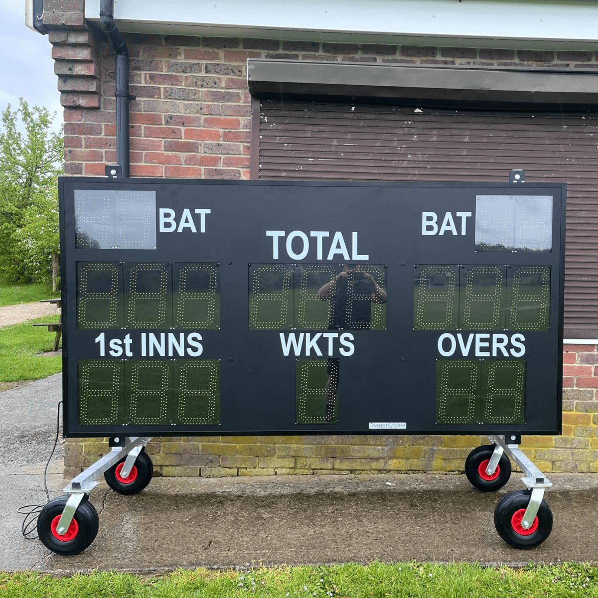 Scoreboard Trolley with digital display showing scores and stats for cricket matches outdoors.